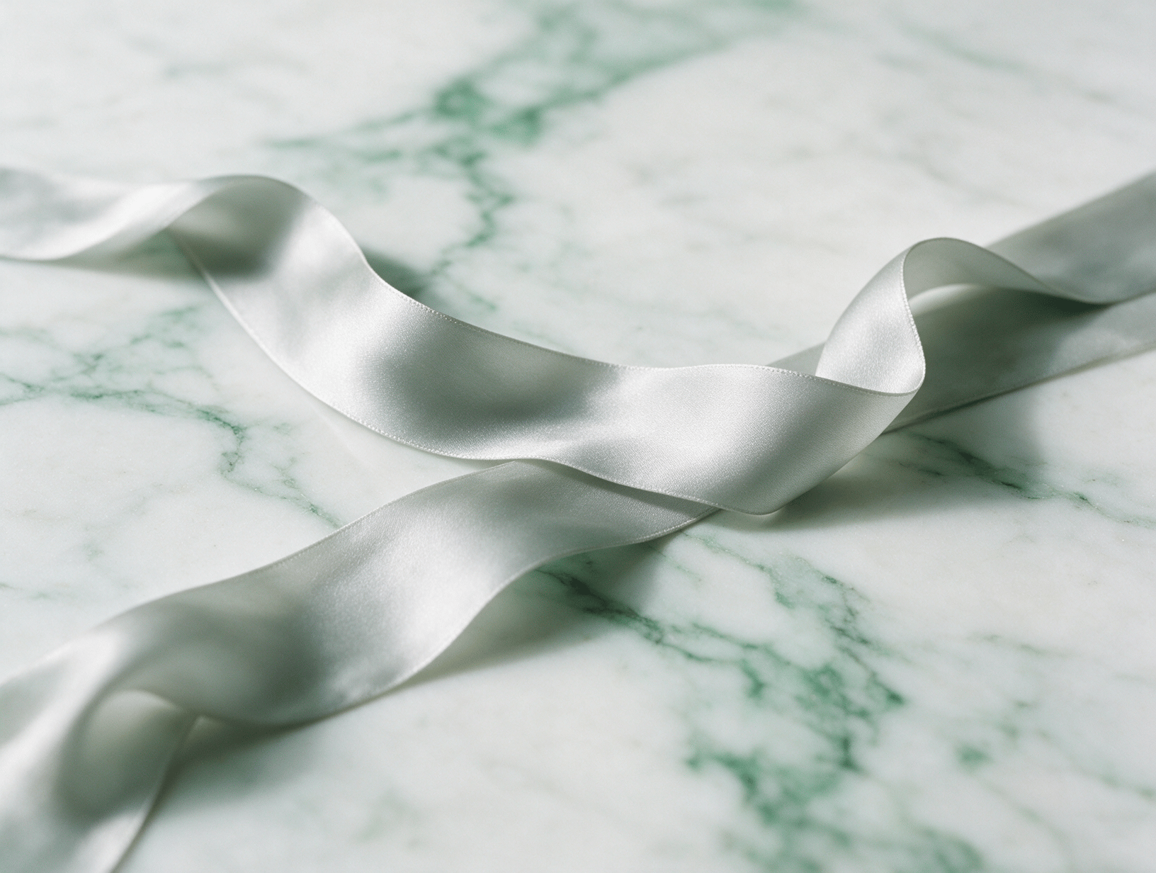 A delicate pale grey silk ribbon on white marble