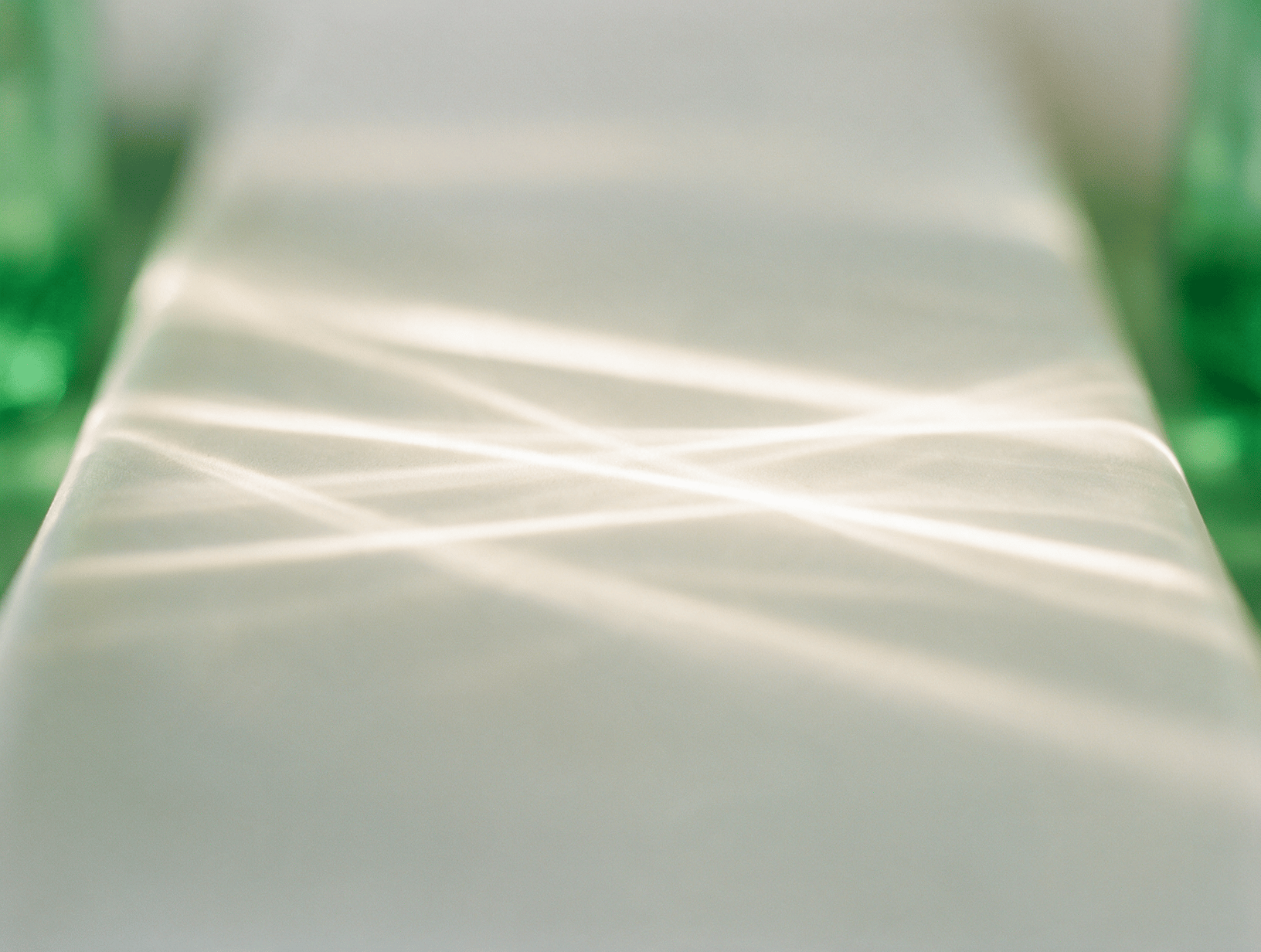 Warm white light beams sweeping across a pale surface
