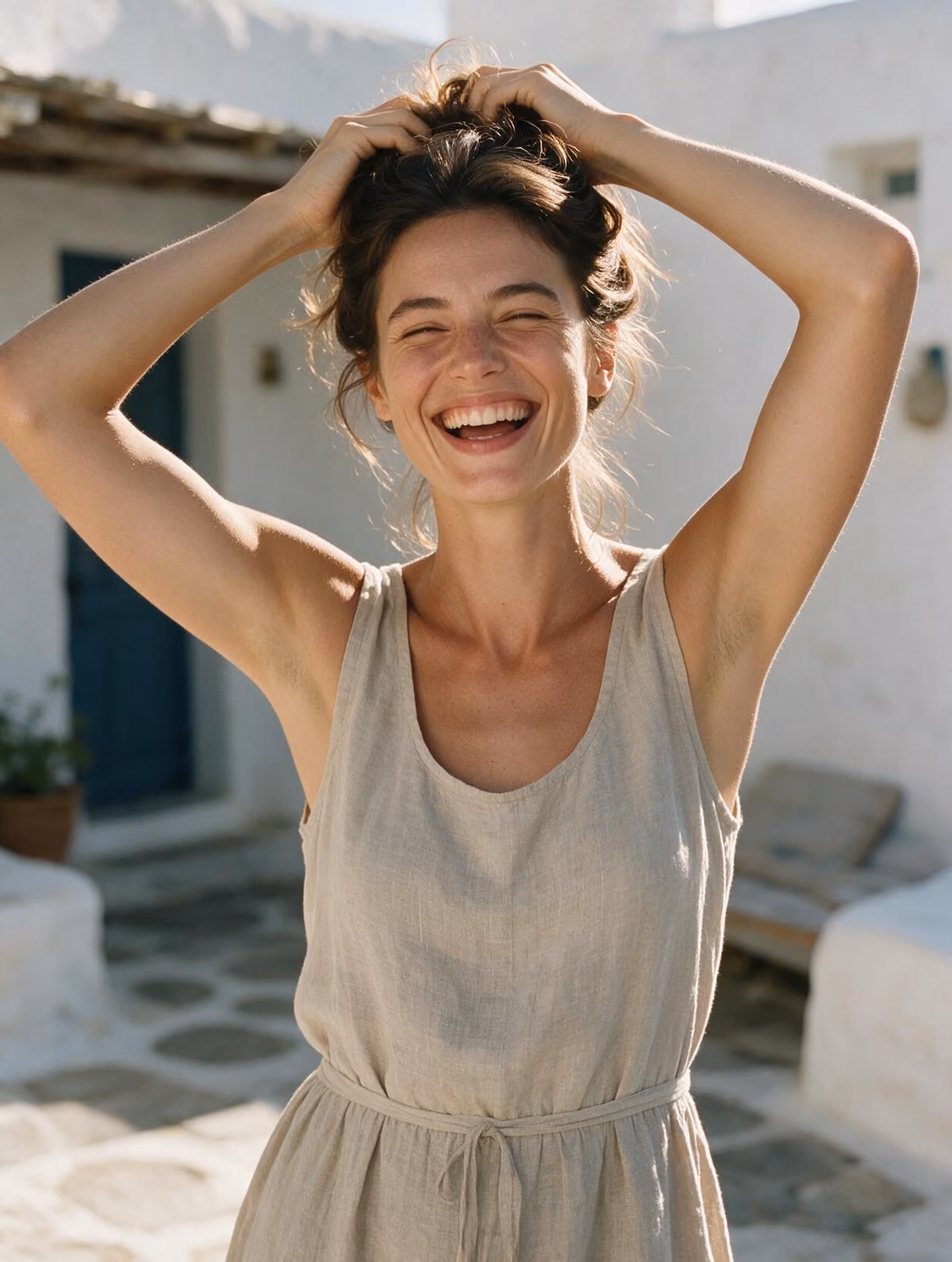 Woman laughing in summer sunlight, arms raised