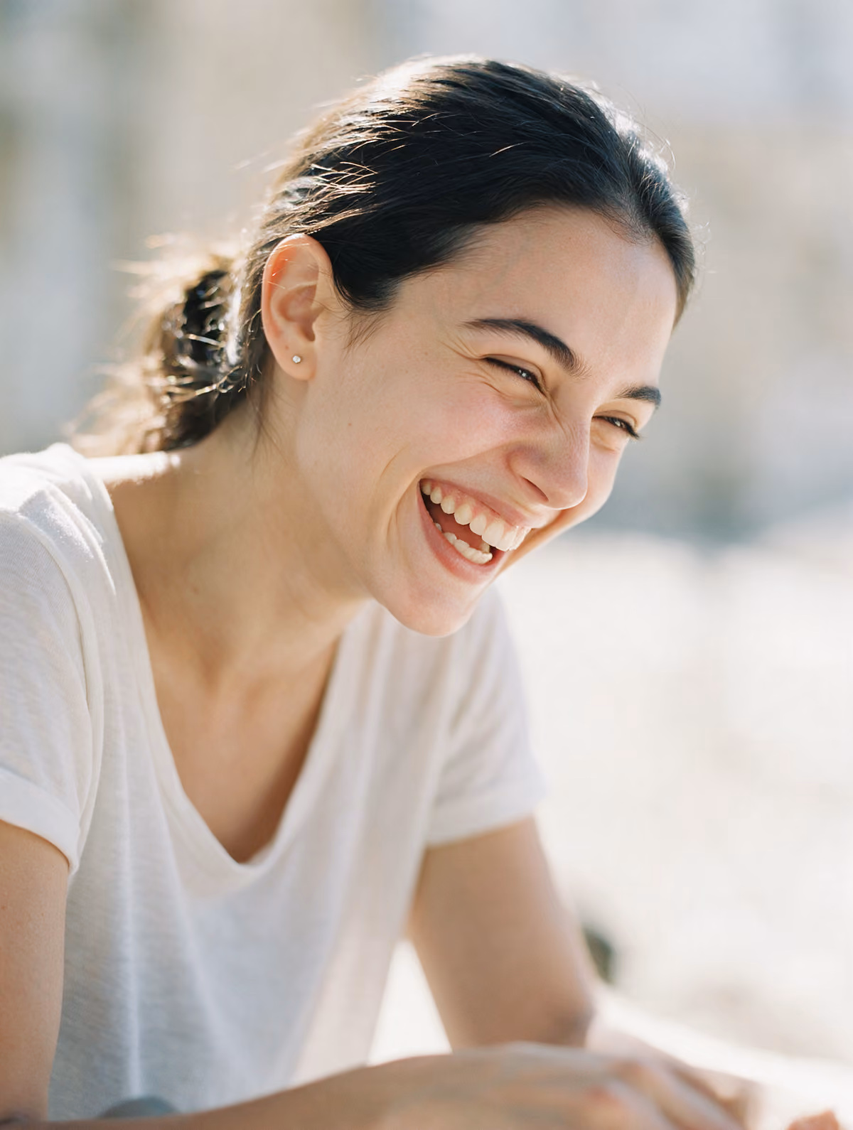 Young woman laughing, wearing a small stud earring